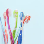 Toothbrushes in glass cup on blue background close-up, copy space.
