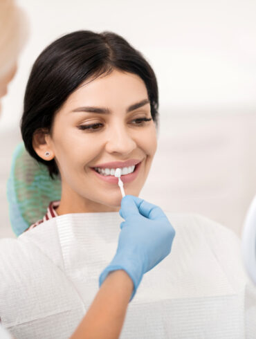 Woman trying on dental veneers sample at dentists.